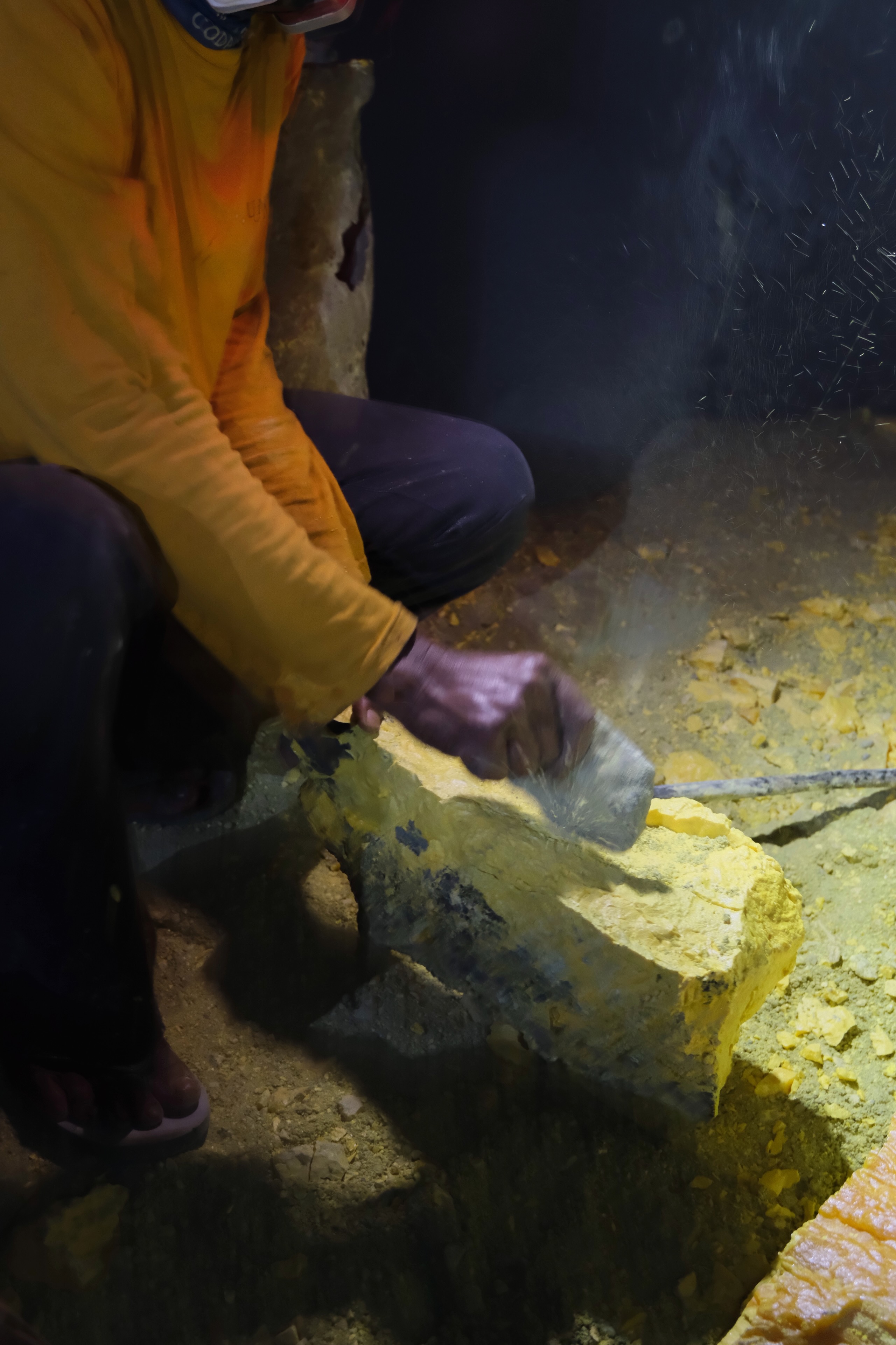 Sulfur miner breaking rock at Kawah Ijen